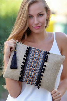 a woman is holding a small pillow with tassels on the front and side