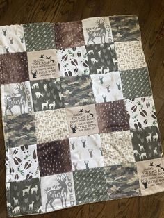 a patchwork quilt on the floor with deer and trees printed on it's side