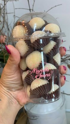 a hand holding a plastic container filled with chocolate covered donuts and marshmallows