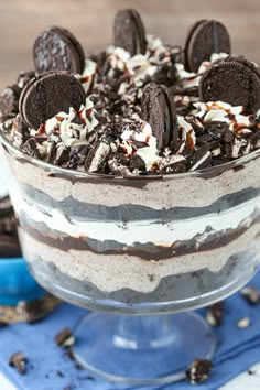 an oreo cookies and cream trifle is shown in a glass dish on a blue napkin