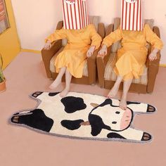 two people sitting in chairs with popcorn bags on their heads and one is wearing a cow costume