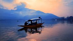 two people in a boat on the water with mountains in the backgrouds