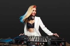 a woman with headphones on standing in front of some dj equipment