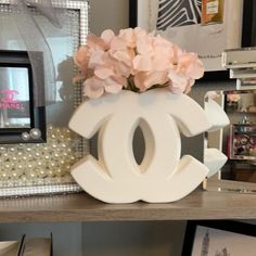 a white vase with flowers in it sitting on a shelf next to pictures and pearls