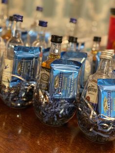 several bottles of alcohol are lined up on a wooden table with confetti in them