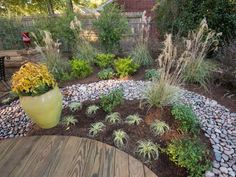 a wooden table sitting next to a garden filled with lots of flowers and plants on top of it