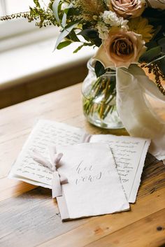 a vase filled with flowers sitting on top of a wooden table next to an envelope