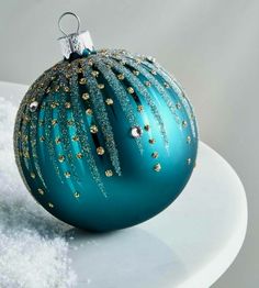 a blue christmas ornament sitting on top of a white plate covered in snow