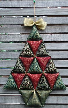 an origami christmas tree hanging on a wooden fence with a bow at the top