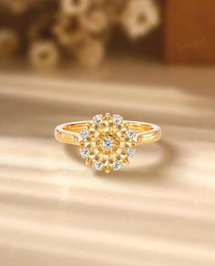 a yellow diamond ring sitting on top of a wooden table with flowers in the background