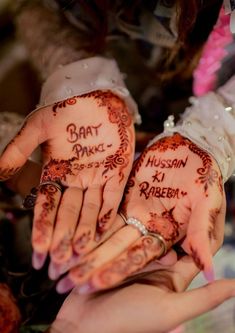 two people holding their hands with hendi tattoos on them and writing on the palms