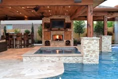 an outdoor living area with a fireplace and grill in the middle, surrounded by a swimming pool