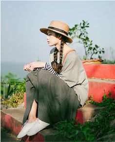 a woman sitting on the steps wearing a hat