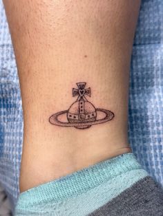 a small tattoo on the ankle of a person with a cross and an object in it