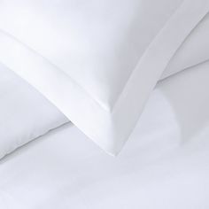 two white pillows sitting next to each other on top of a bed with white sheets