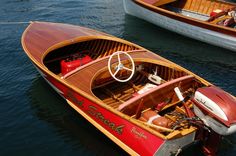 two small wooden boats in the water near each other, one red and one white