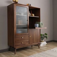 a wooden cabinet sitting on top of a hard wood floor next to a potted plant