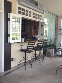 an outdoor bar with four chairs and a refrigerator