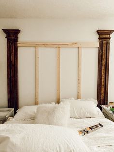 an unmade bed with white pillows and wooden headboard made out of plywood