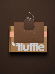 a brown box with white lettering on it and a paper clip hanging from the top