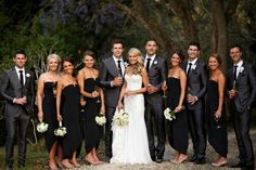 a group of people standing next to each other in front of trees and bushes at a wedding