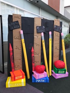 several different colored pencils and crayons are on display in front of a building