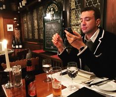 a man sitting at a table taking a photo with his cell phone in front of him