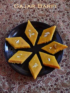 four pieces of cake sitting on top of a black plate with almonds in the middle