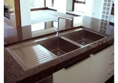 a stainless steel sink in a kitchen with granite counter tops