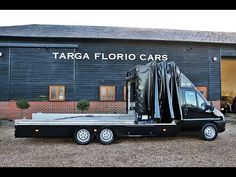 a black truck parked in front of a building with targa fabric cars on it's flatbed