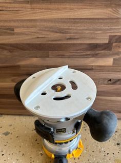 the bottom part of an electric grinder on top of a wood floor with a wooden wall behind it