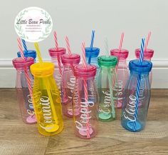 there are many different colored drinking bottles with straws in them and one has a name on it