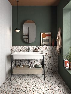 a bathroom with a sink, mirror and tiled flooring in green tones on the walls