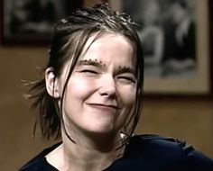 a woman with long hair and piercings on her forehead smiles at the camera while wearing a black shirt