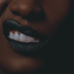 a woman's mouth with white teeth and black lipstick on the lips is shown