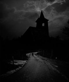 a dark road with a church in the background