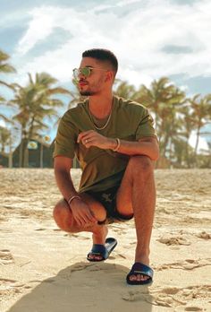 a man sitting in the sand with sunglasses on