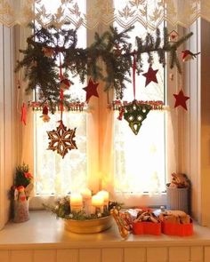 a window with christmas decorations hanging from it's sides and candles on the windowsill