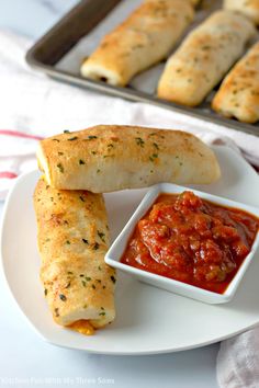 some bread sticks are on a plate with sauce