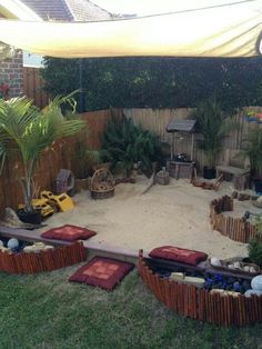 an outdoor area with sand and plants in the back yard, surrounded by wooden fences