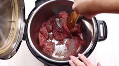 a person stirring meat in a pot on the stove