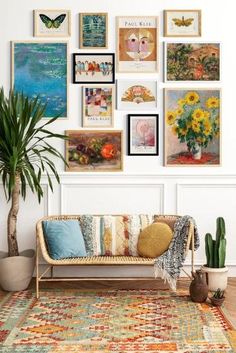 a living room with lots of pictures on the wall and a couch next to a potted plant