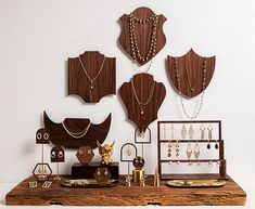 a table topped with lots of jewelry on top of a wooden table next to a white wall