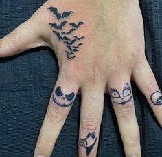 a person's hand with tattoos on it and two bats flying over the fingers