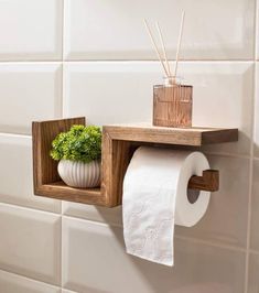 a wooden shelf holding two rolls of toilet paper and a potted plant in it