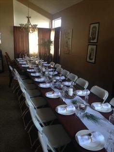 a long dining table with white plates and silverware set for an elegant dinner party