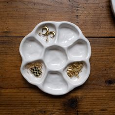 a white plate with gold rings on it sitting on top of a wooden table next to other items