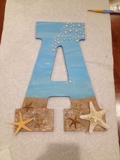 the letter a is made out of wood and decorated with starfish