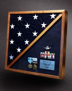 an american flag and medal display in a wooden frame on a black background with white stars