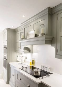 a kitchen with gray cabinets and white counter tops